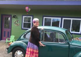 Dianne Burger poses in front of a VW bug car.