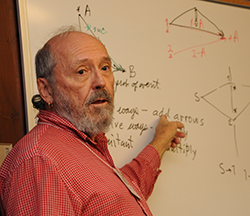 George Angwin teaches in front of a white board.